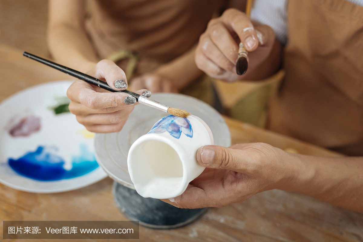 两个艺术家在小陶罐上画花